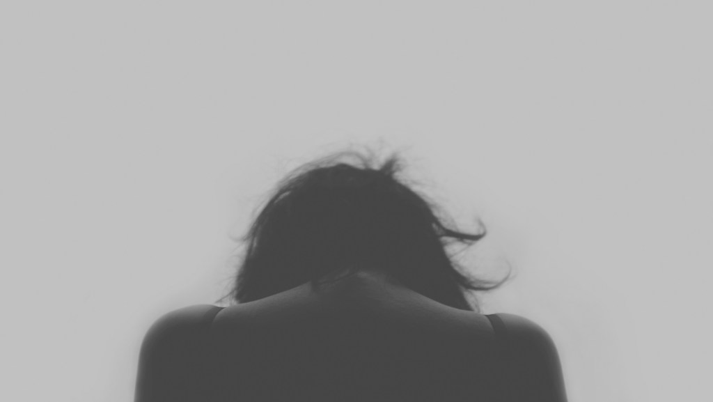a woman with head down in grayscale